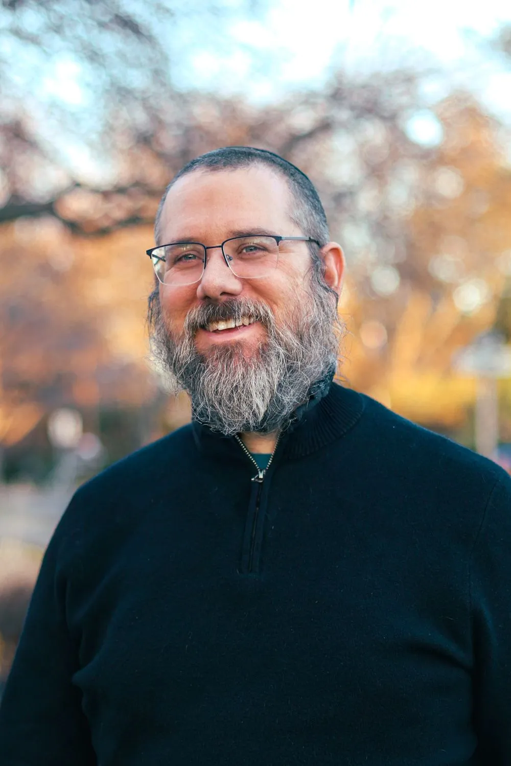 Aaron Silverman smiling outdoors in autumn light